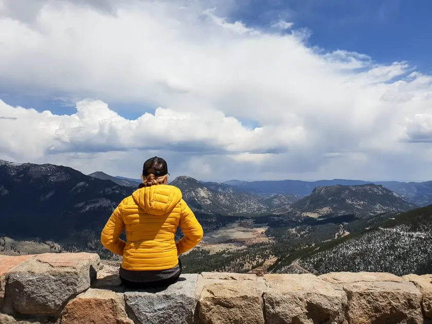 woman in yellow jacket looking at rocky mountain national park