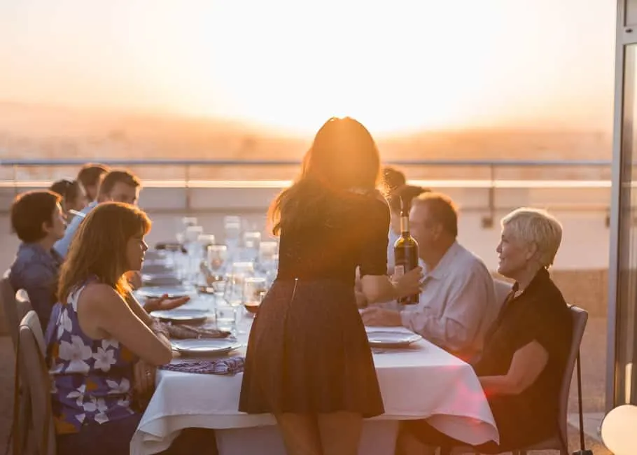 group of people dining in a rooftop restaurant at sunset