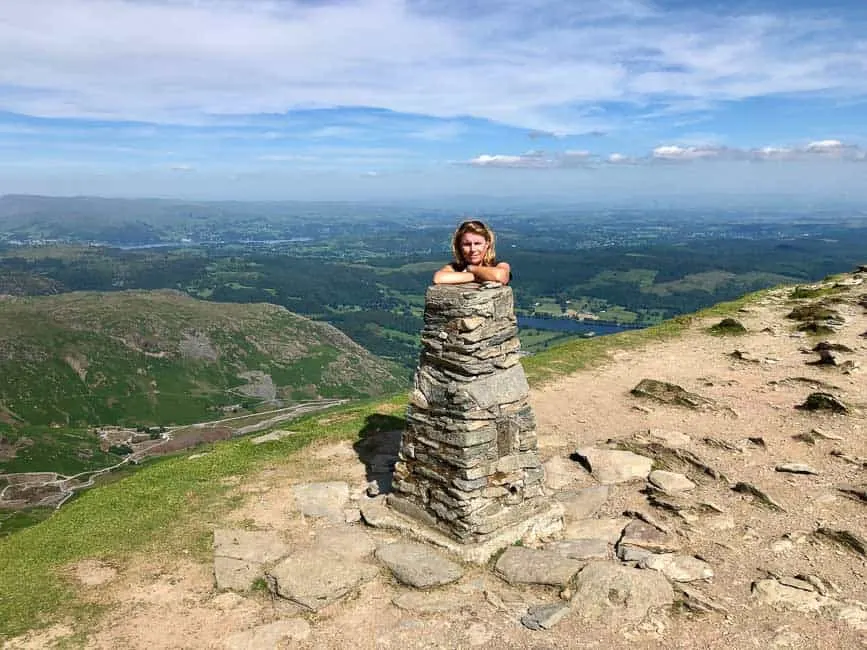 woman looking over Coniston Old Man Trig point