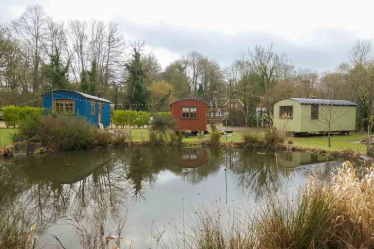 Three shepherd huts around a pond