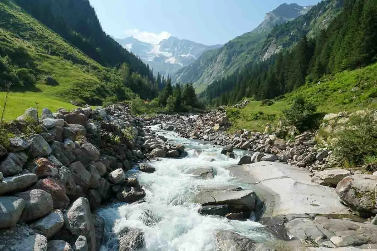 Stilluptal nr Mayrhofen, Austria. A brook gushes through the centre of a green valley with a snow-capped mountain in the background
