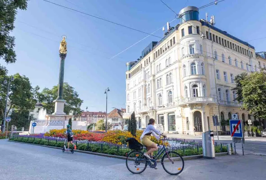 Woman cycliing past colourful flower borders in Graz, Austria