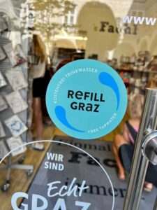 Sticker on shop window with the refill Graz logo showing you can refill your water flask for free