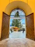 Looking through a large arched doorway onto Residenzplatz where a huge Christmas tree and Christmas market stalls can be seen