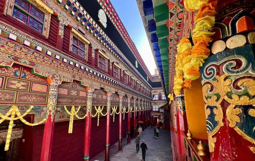 Inside the main entrance of Dege Parkhang Sutra-Printing House where painted columns and the traditional Tibetan building are decorated with fabric swathes of yellow and orange flowers