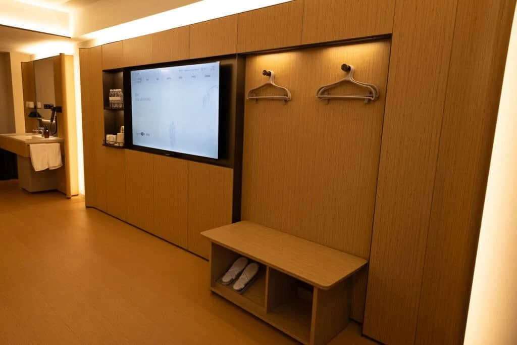 Modern Ji Hotel room in Yushu, China, with a large TV, wooden wall unit, and vanity.