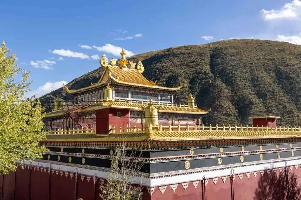 The gold rooftops of Xianggu Temple in China with green hills in the background
