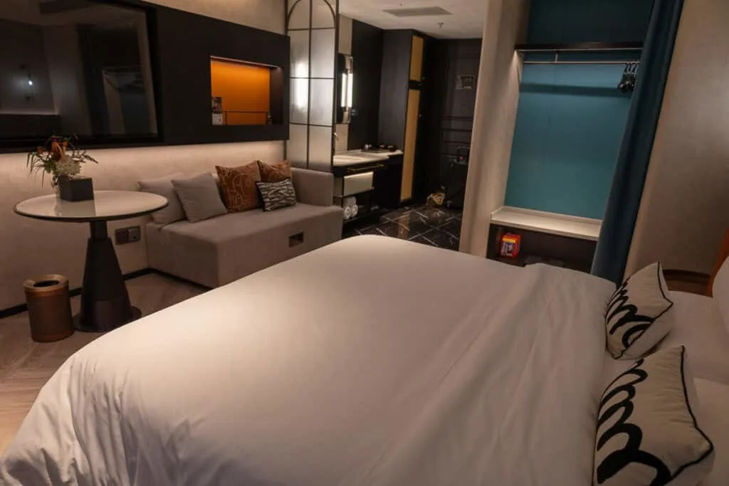 A modern hotel room at the Ailunge Garden Hotel in Xining, China, featuring a bed, sofa, and stylish decor.