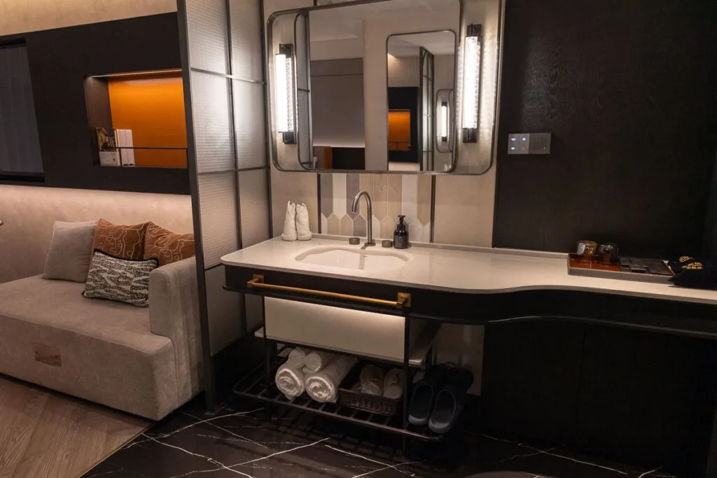 Stylish bathroom vanity with a sink, mirror, and sofa in a room at Ailunge Garden Hotel Xining.