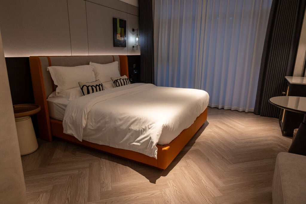 Modern hotel room with an orange bed frame and white bedding at Ailunge Garden Hotel in Xining.