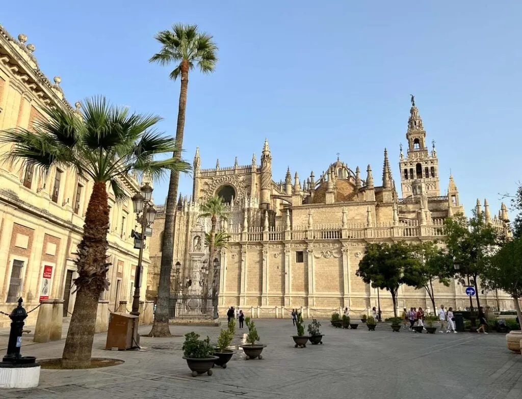 Seville Cathedral with palm trees in front and a blue sky background