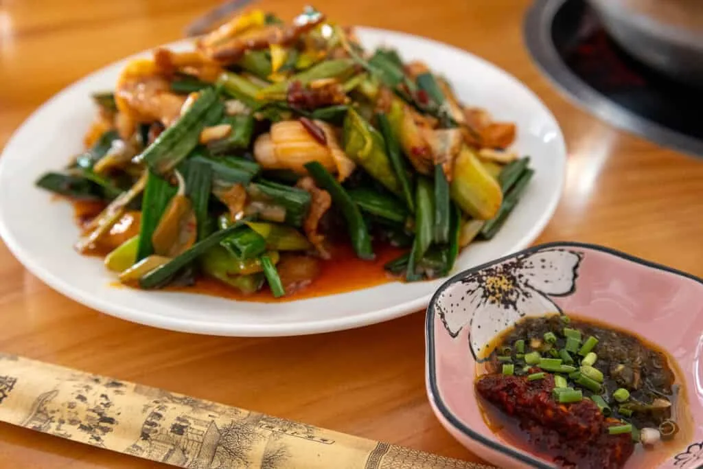 vegetable Stir fry dish with Chilli sauce on a wooden table. A paper packet holds the chopsticks