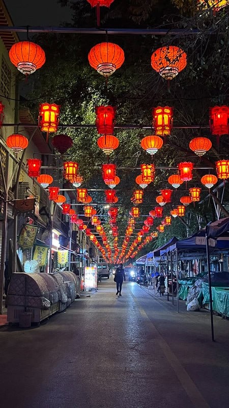A vibrant night market street in Xining, China, illuminated by numerous glowing red Chinese lanterns.