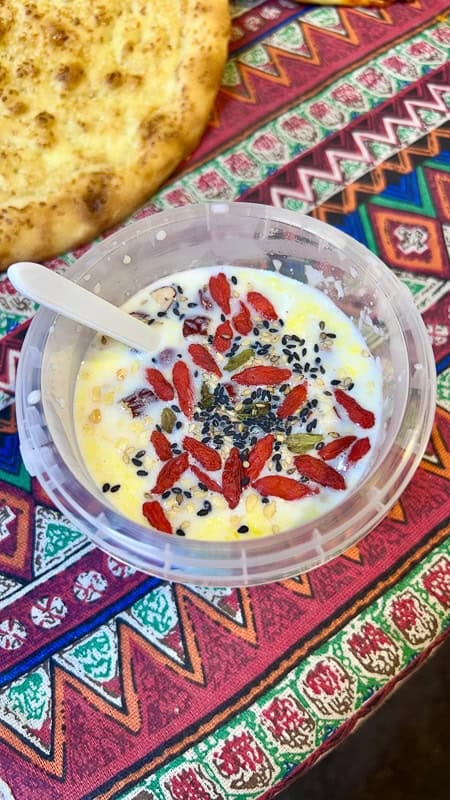 A Xining night market dessert with goji berries, sesame seeds, and flatbread on a colorful patterned textile.