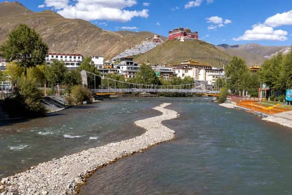 Jiegu Monastery on a hill above a river and town with a suspension bridge in Yushu, China.