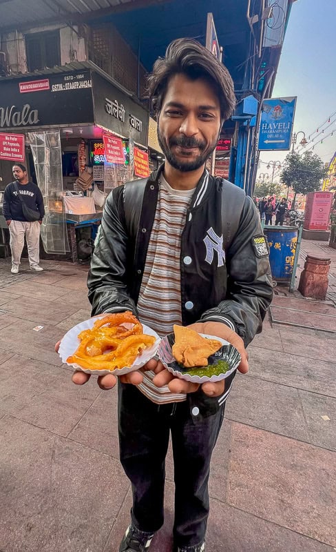 A man holds jalebi and samosa on a street in Old Delhi