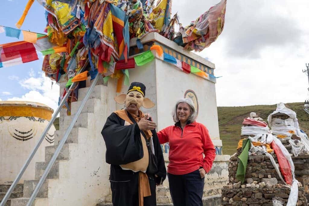 A man dressed as a pig and a woman in a red sweat top standing in front of a stupa in China