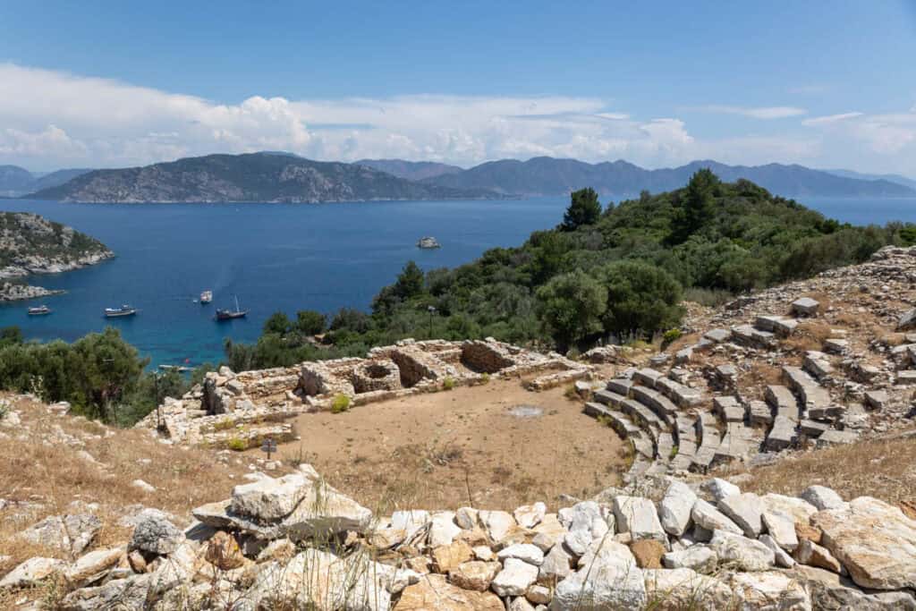 Historic stone amphitheatre with the blue sea of Marmaris Bay in the background, Turkey. Therea re tree covered hills in the background