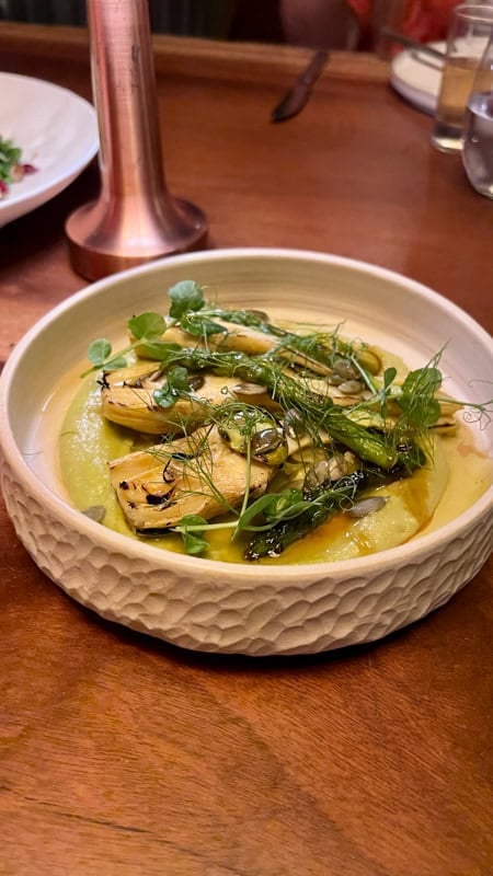 Artichoke heart salad with capers in a round china dish on a wooden table