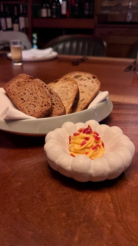 A dish of sliced bread with a swirl of butter in a side dish