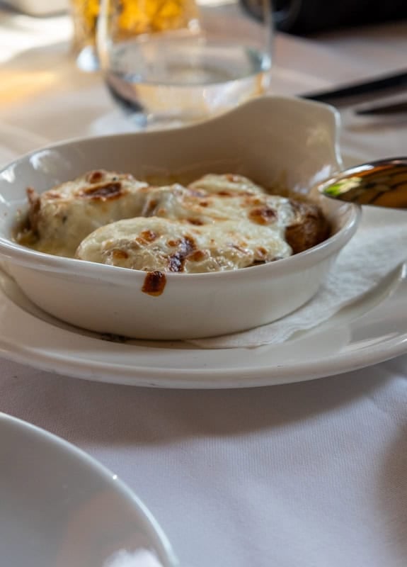 A dish of cheese covered baked mushrooms. The cheese has melted and browned in places