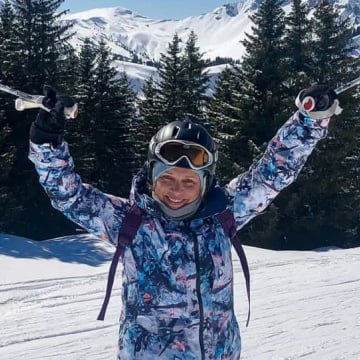 Woman in ski gear holding ski poles in the air
